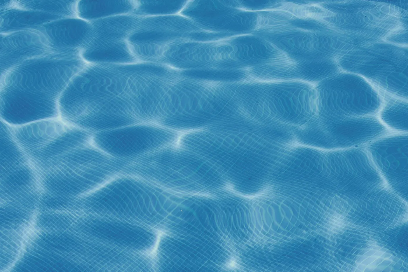 Sunlight rippling across clear blue pool water