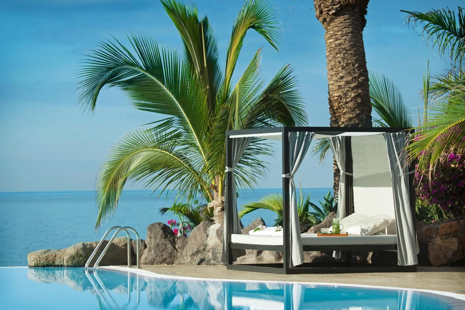 Daybed beside the pool under palms