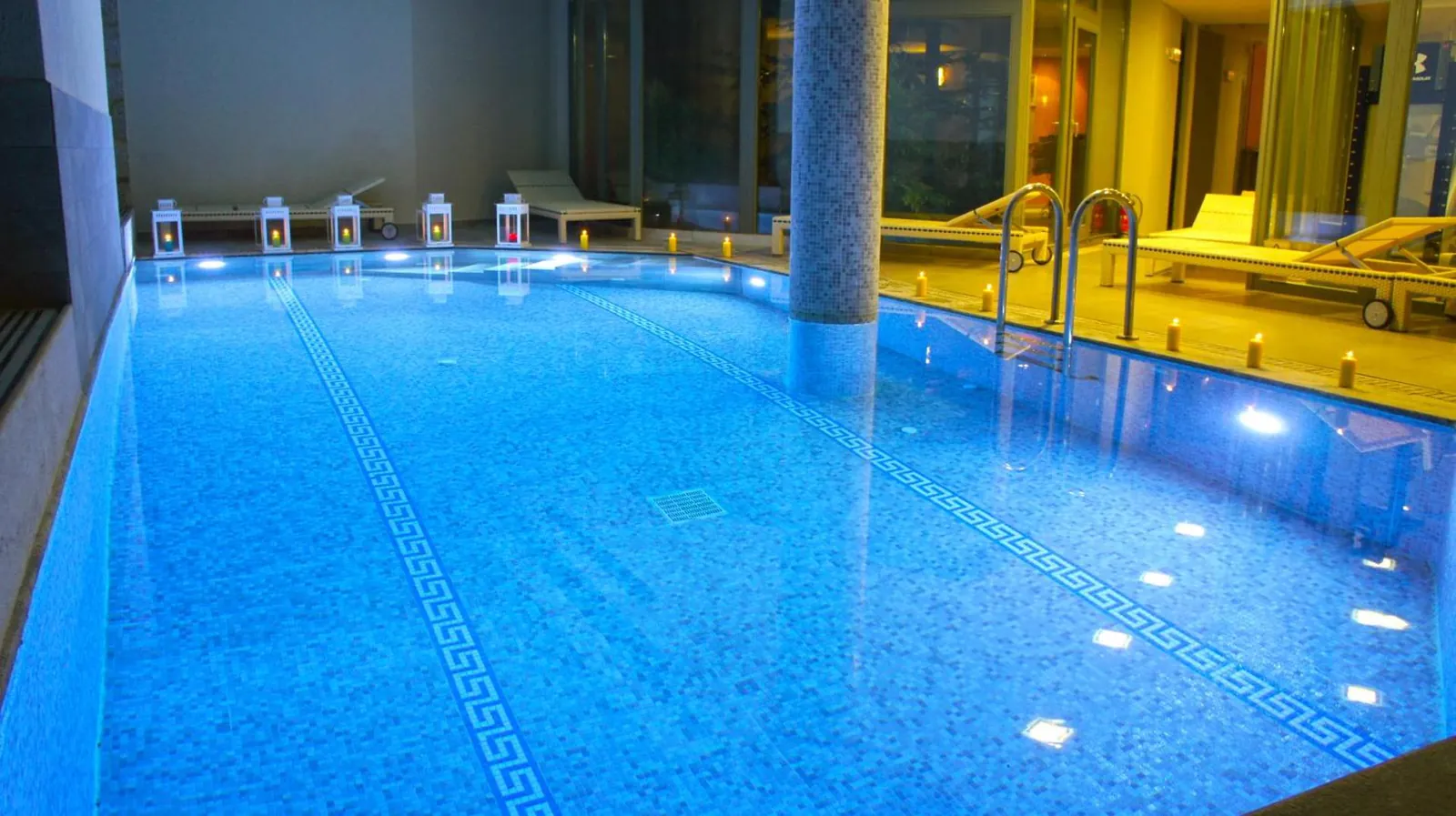 Indoor pool lit blue with loungers along the far edge at Aegli Arachova