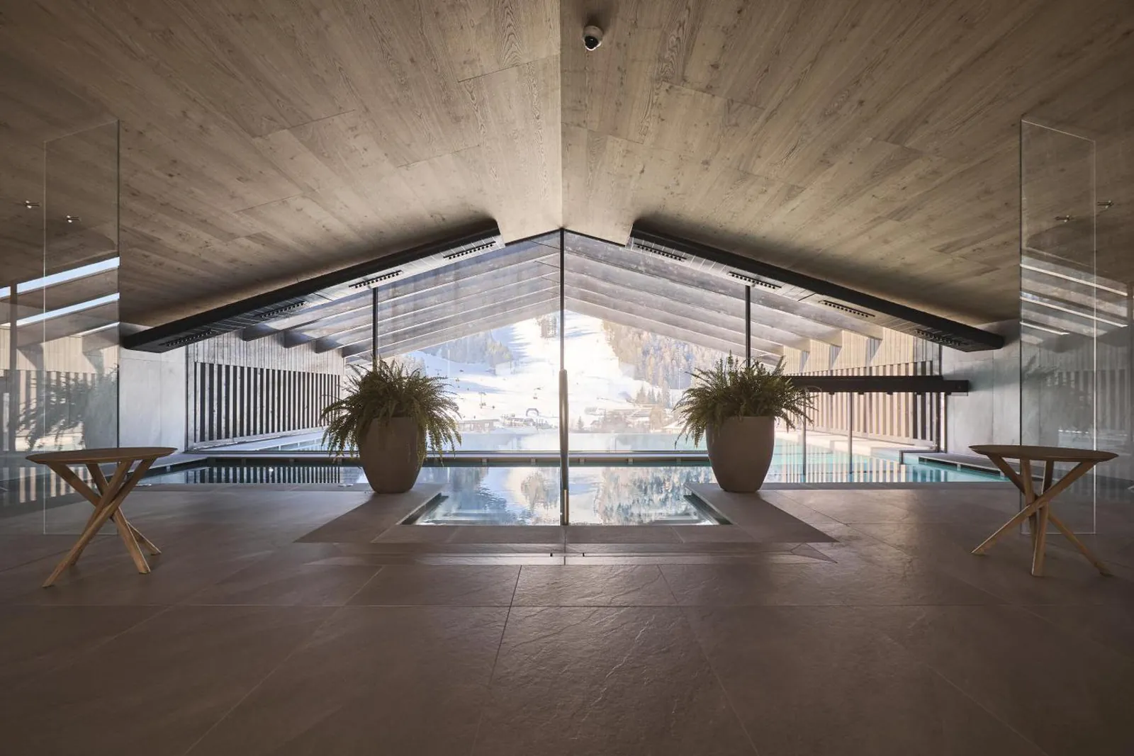 Indoor section of the rooftop pool at AMA Stay, glass wall facing the Dolomites