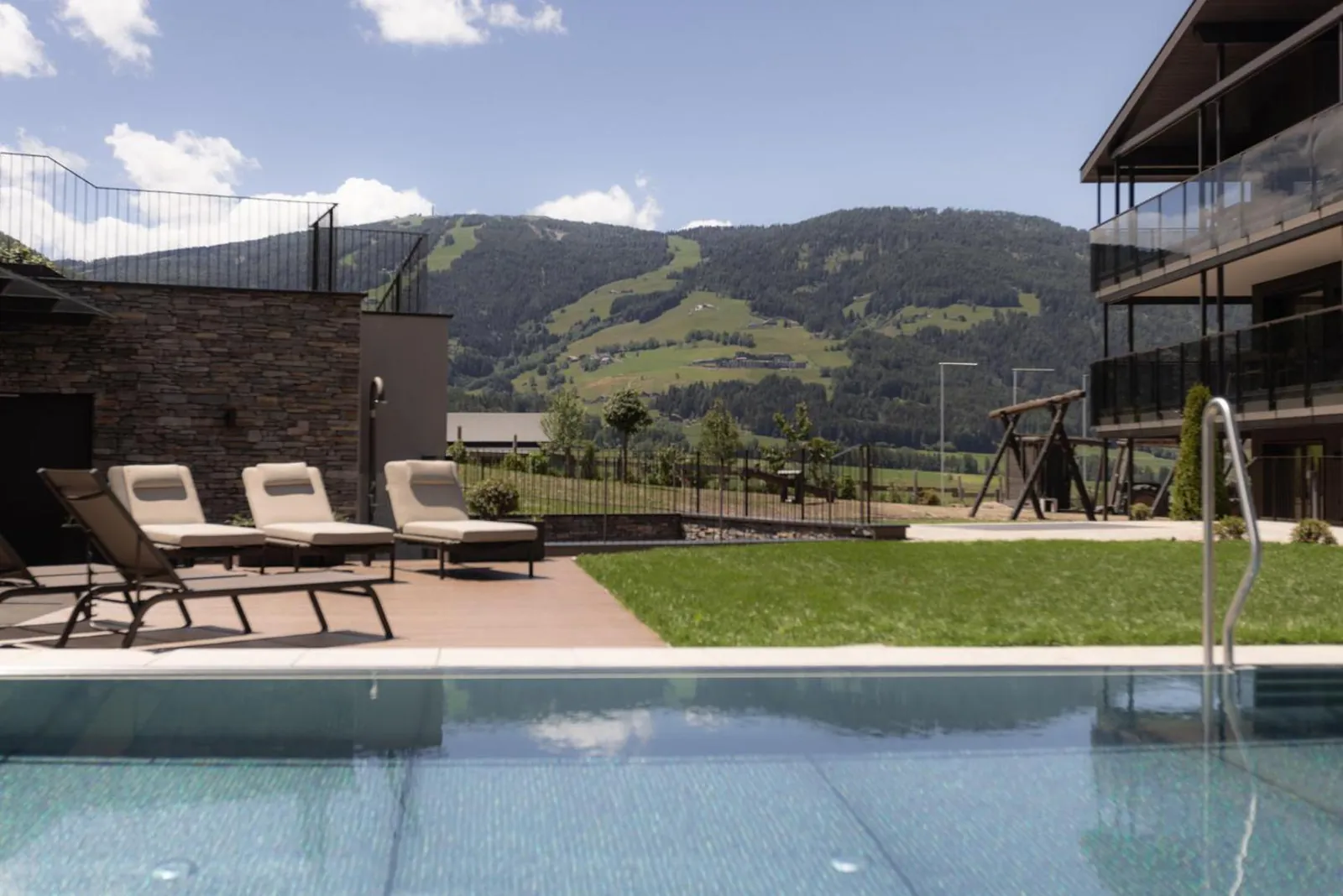 Outdoor pool edge with loungers and mountains behind