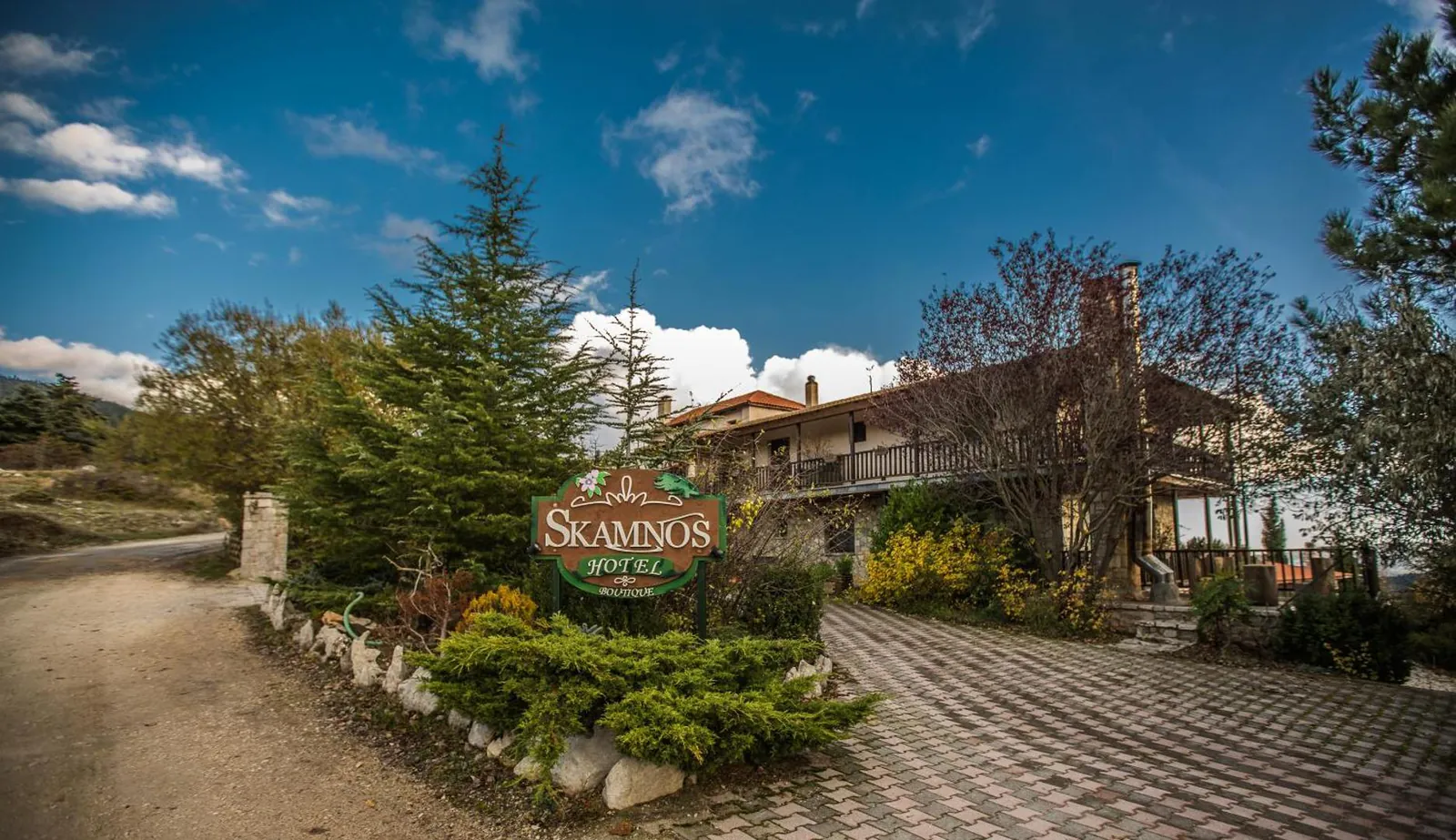 Hotel entrance path with the Skamnos sign among pines