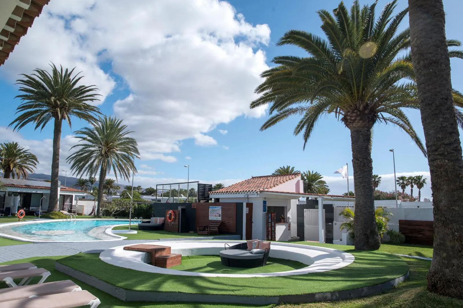 Pool and a sunken seating area on the lawn between the palms