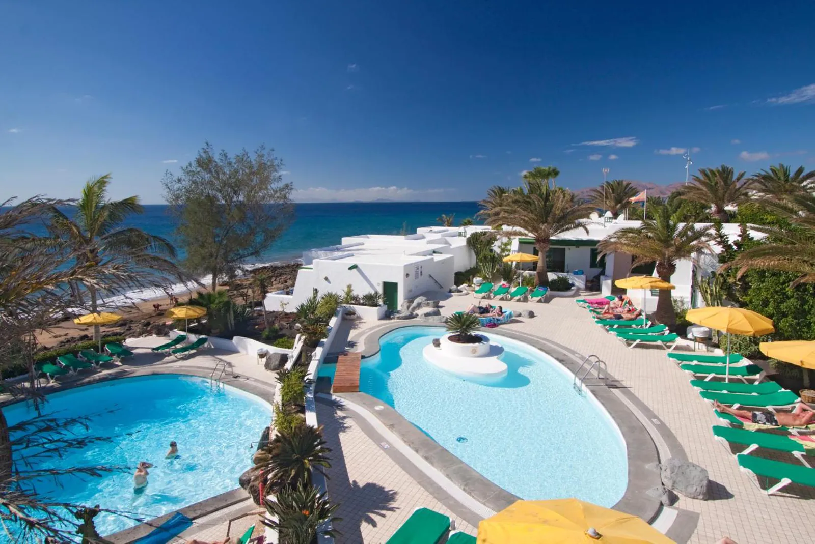 The two pools side by side, ringed by loungers, with the Atlantic beyond