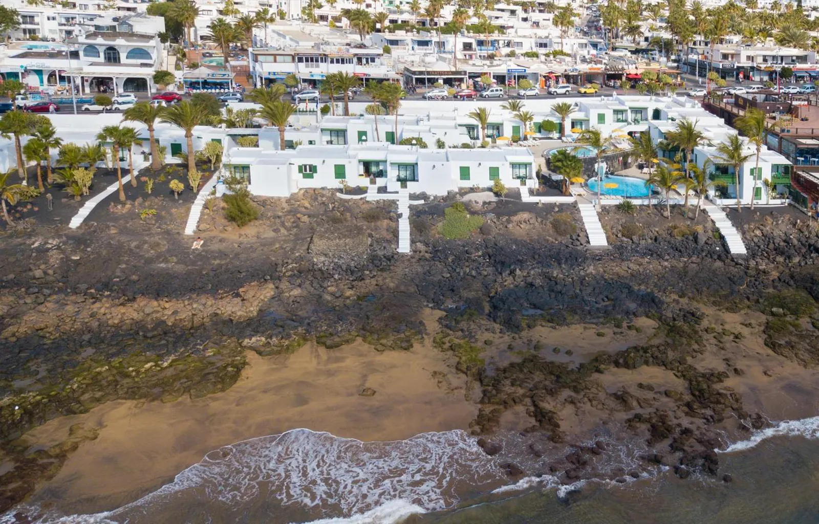 Aerial view of the low white bungalows on the lava shore