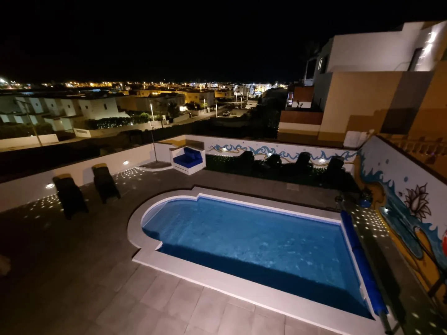 The private pool lit up at night with the town lights beyond
