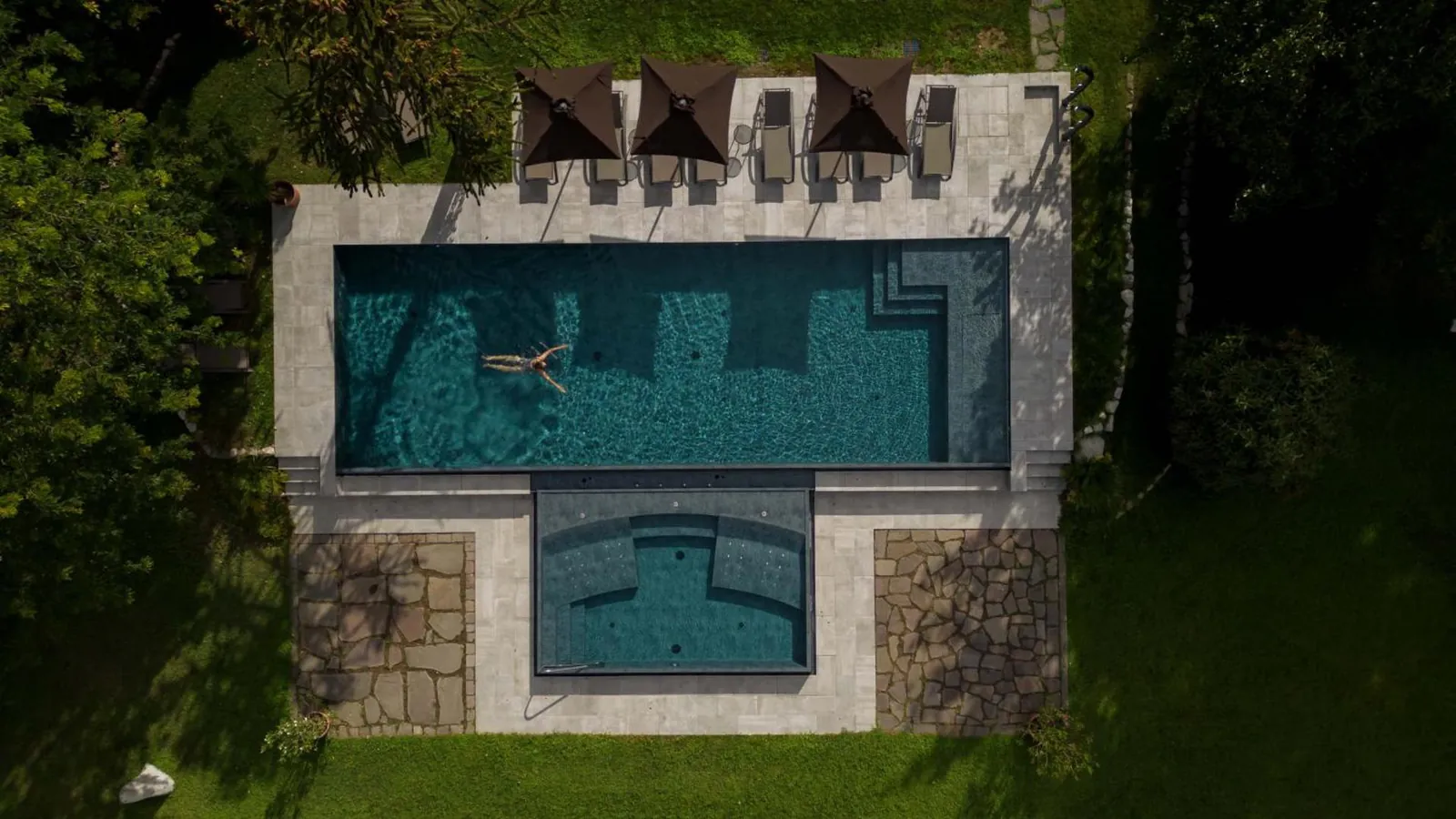 Aerial view of the outdoor pool and its whirlpool section set in green lawn