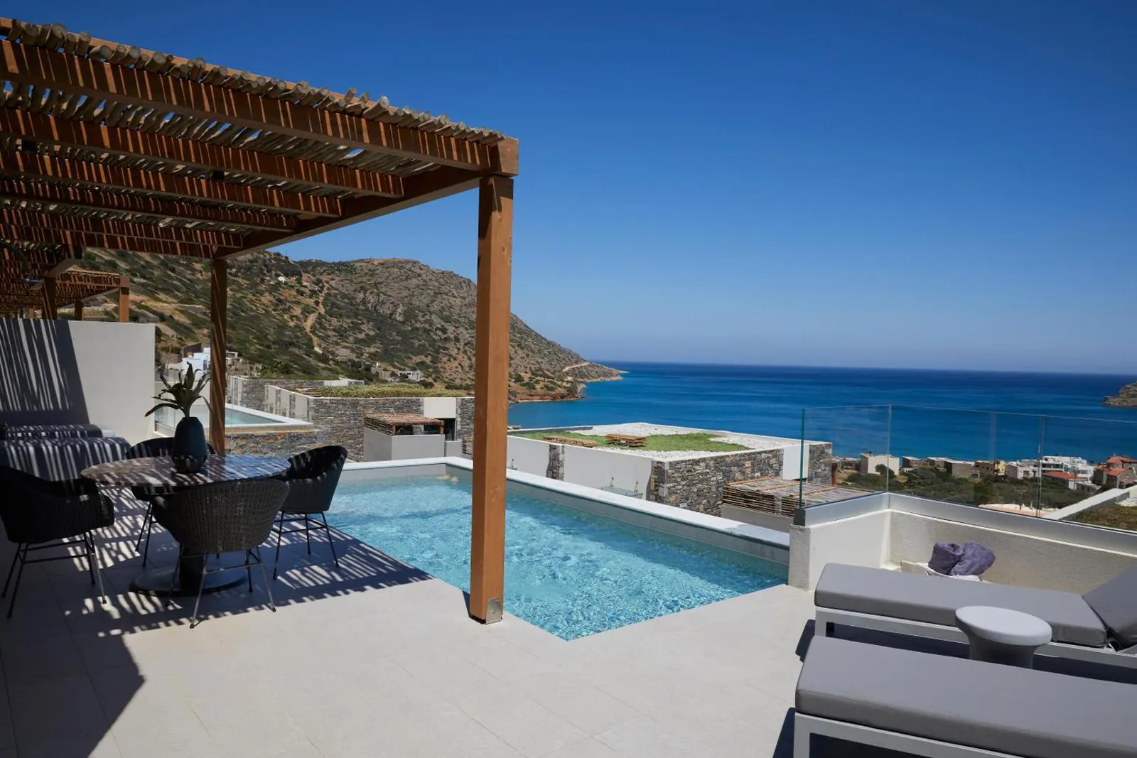 Private pool terrace with loungers and a wide view over the sea