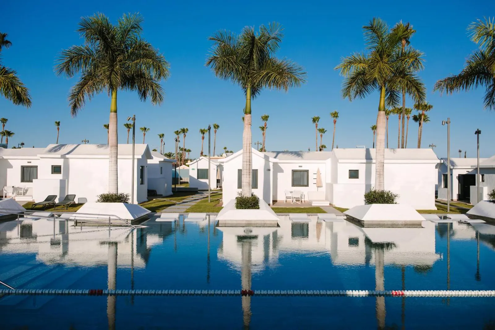 Long pool lined with palms and white bungalows at Club Maspalomas Suites & Spa