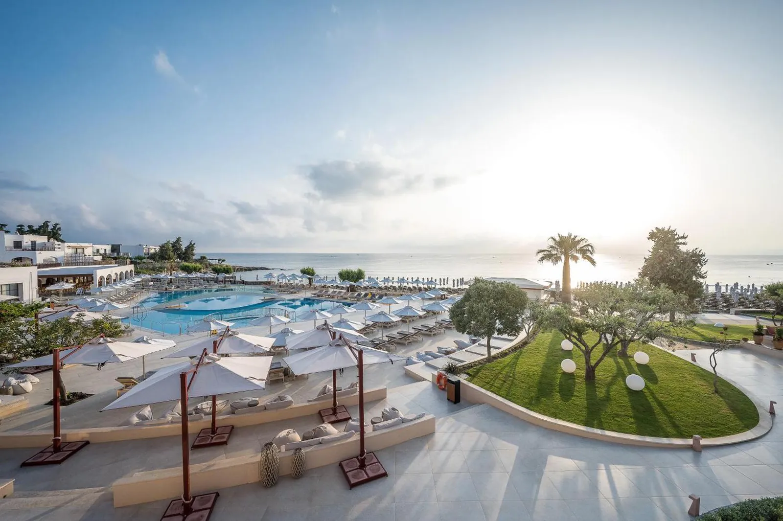 Pool terrace and lawn running down towards the sea at sunrise