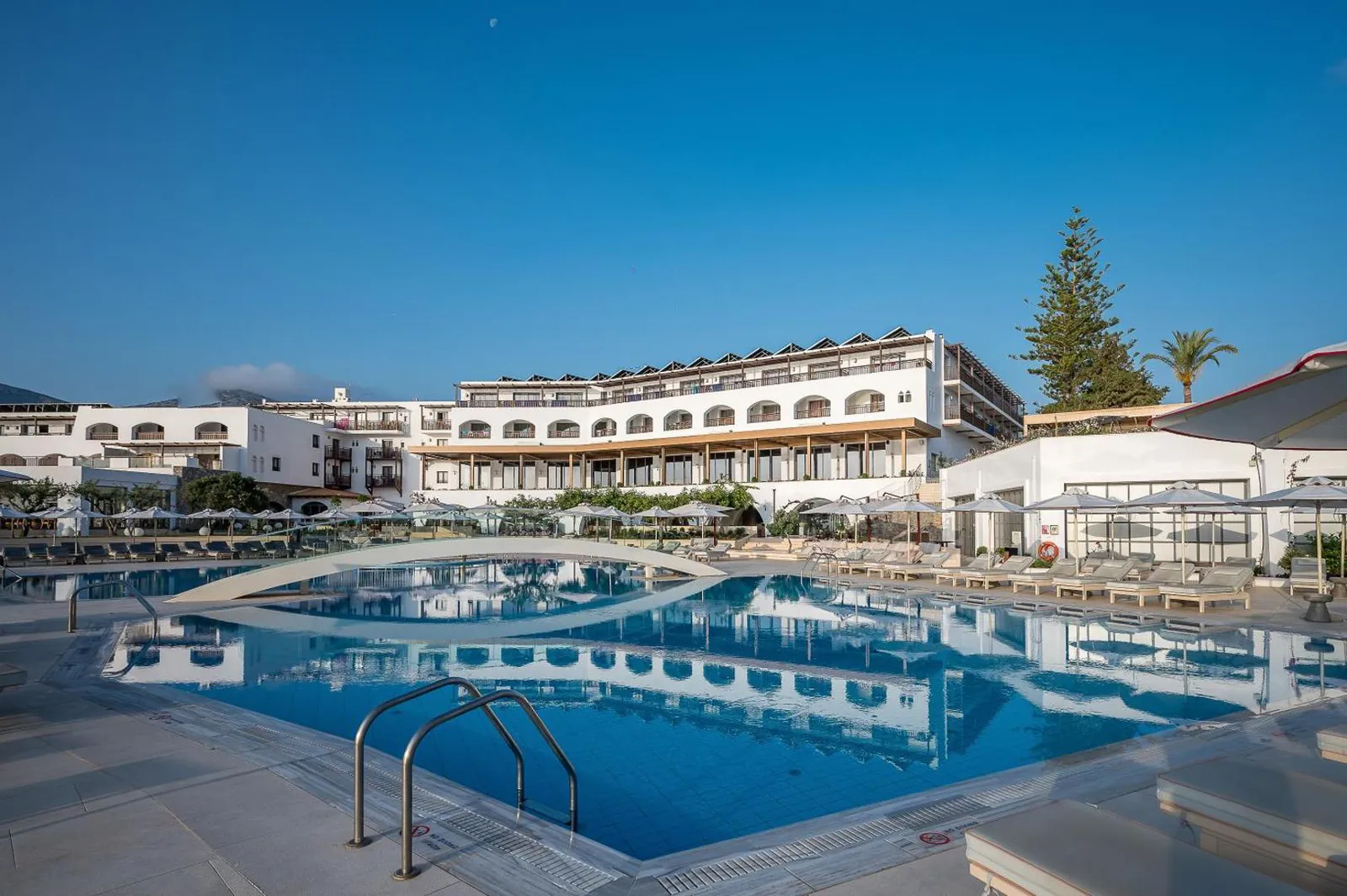 Long outdoor pool in front of the white resort buildings