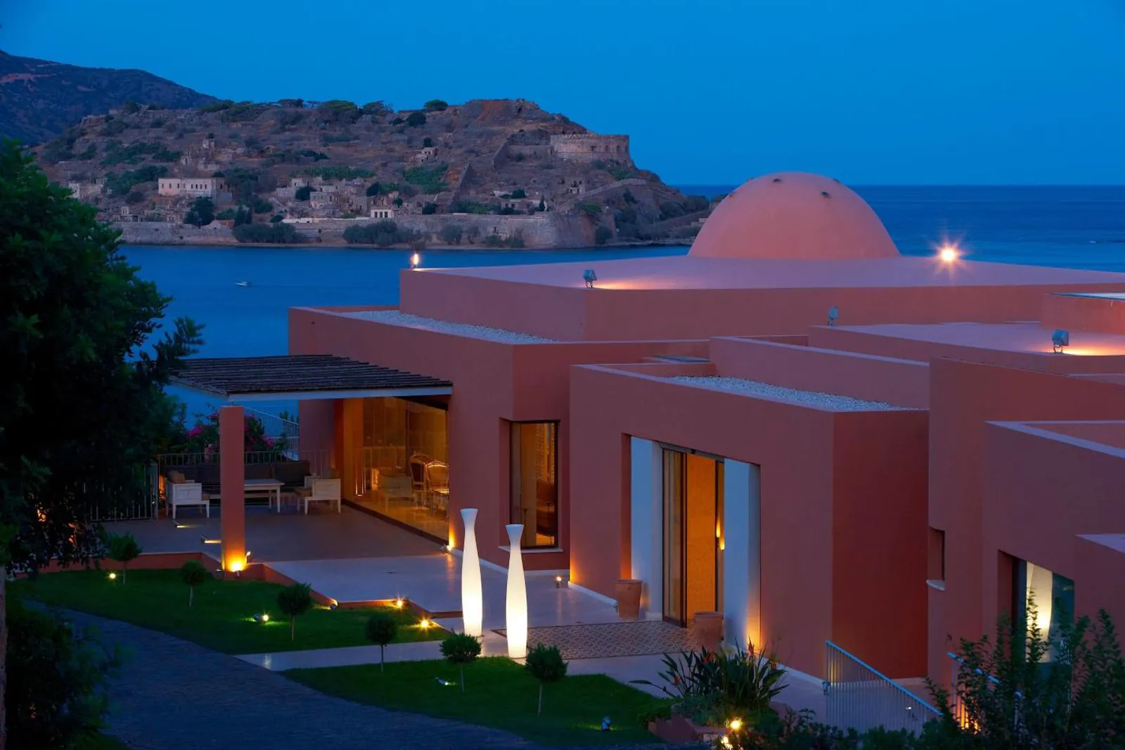 Domed building lit at dusk with Spinalonga across the water