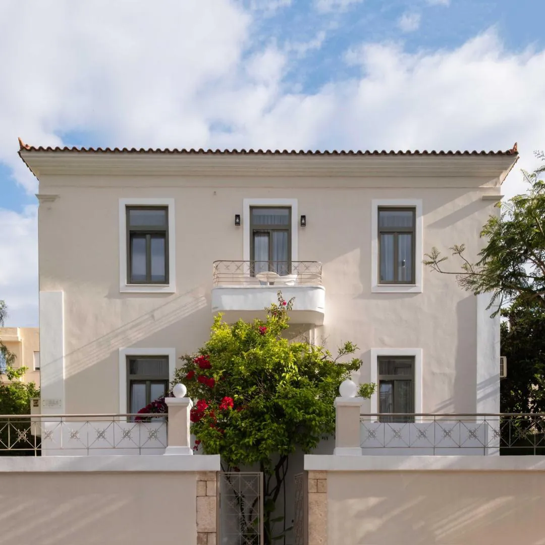Neoclassical facade of Epavli with a balcony and flowering shrubs