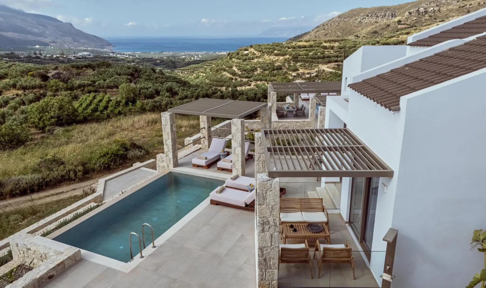 View down onto a villa's pool and terraces on the slope above Kissamos Bay