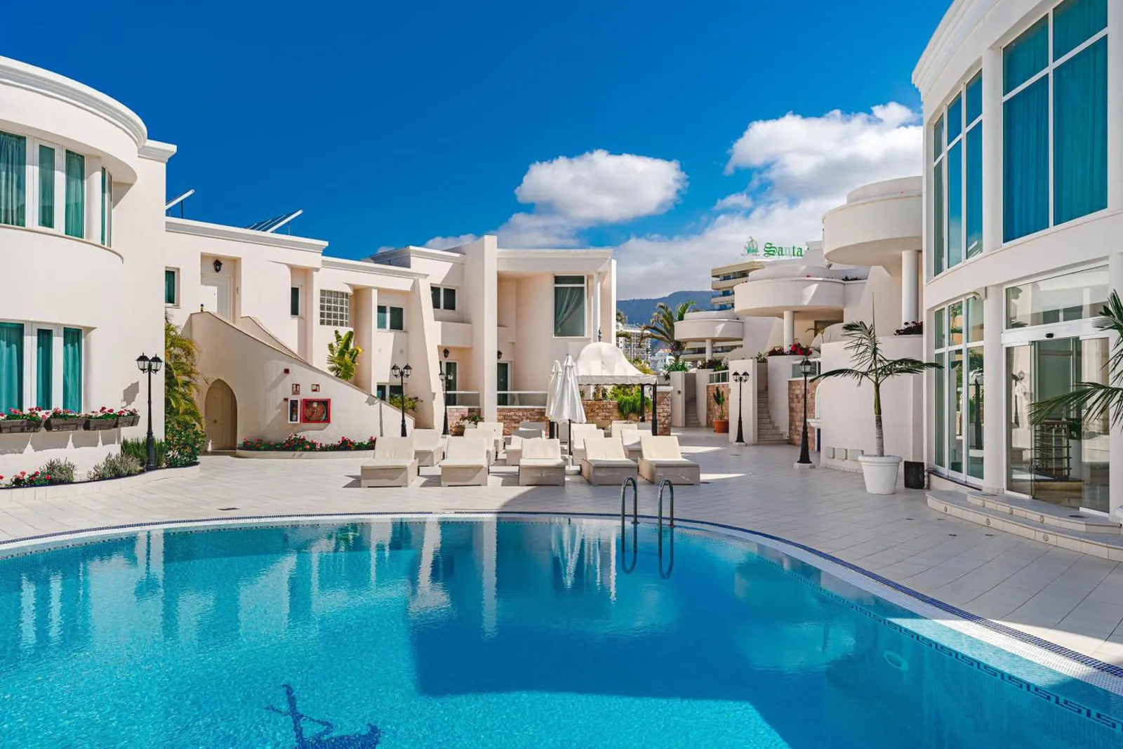Curved outdoor pool with loungers and white apartment buildings