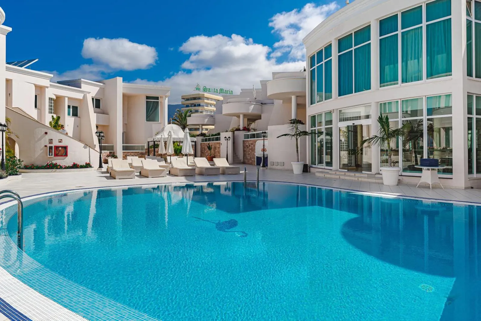 Pool with loungers in front of the glazed suite corner
