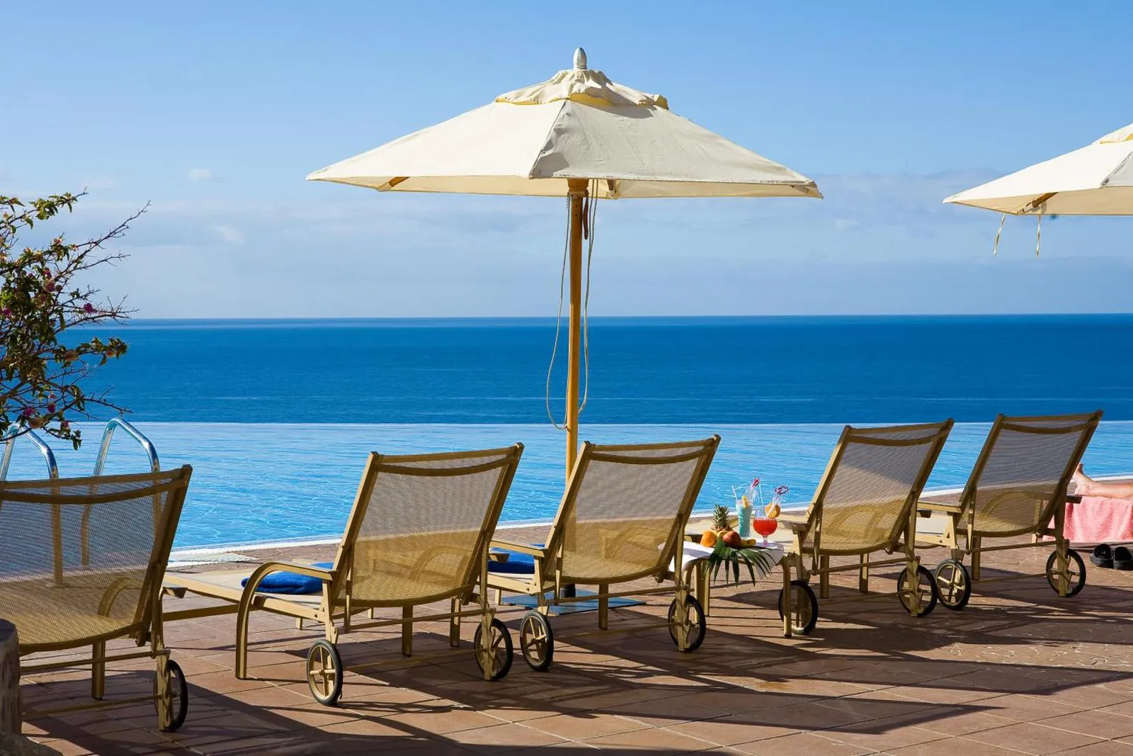 Loungers and parasols along the pool edge facing the open sea
