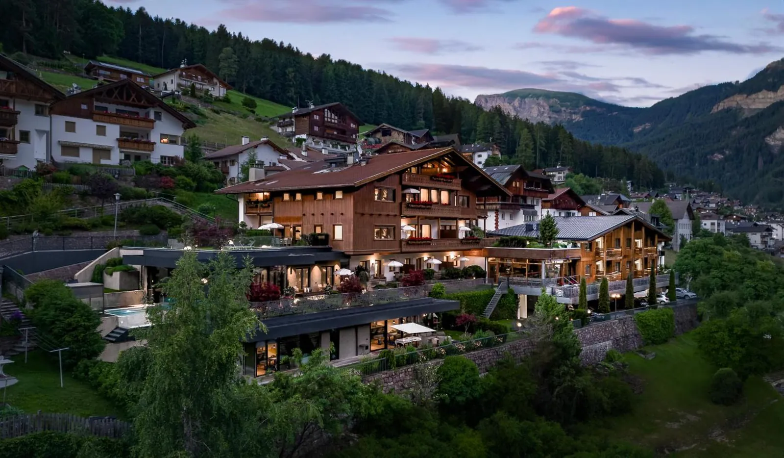 Gran Tubla's chalet-style buildings on the hillside above Ortisei in the evening