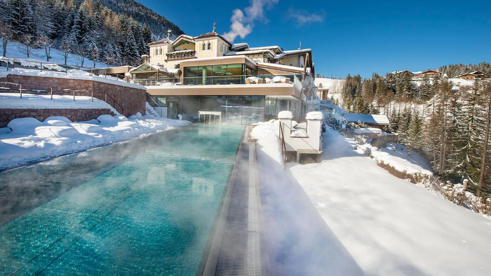 Outdoor pool edged with snow below the hotel terraces in winter
