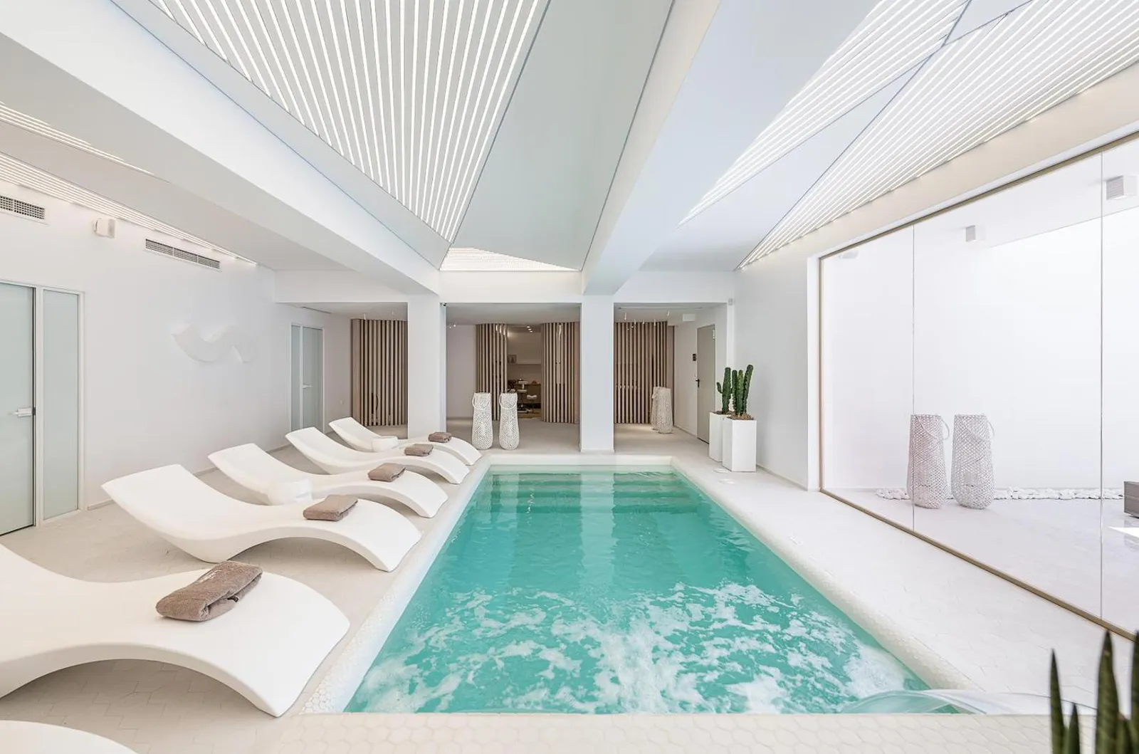 Indoor saltwater pool lined with white loungers in the Lagon spa