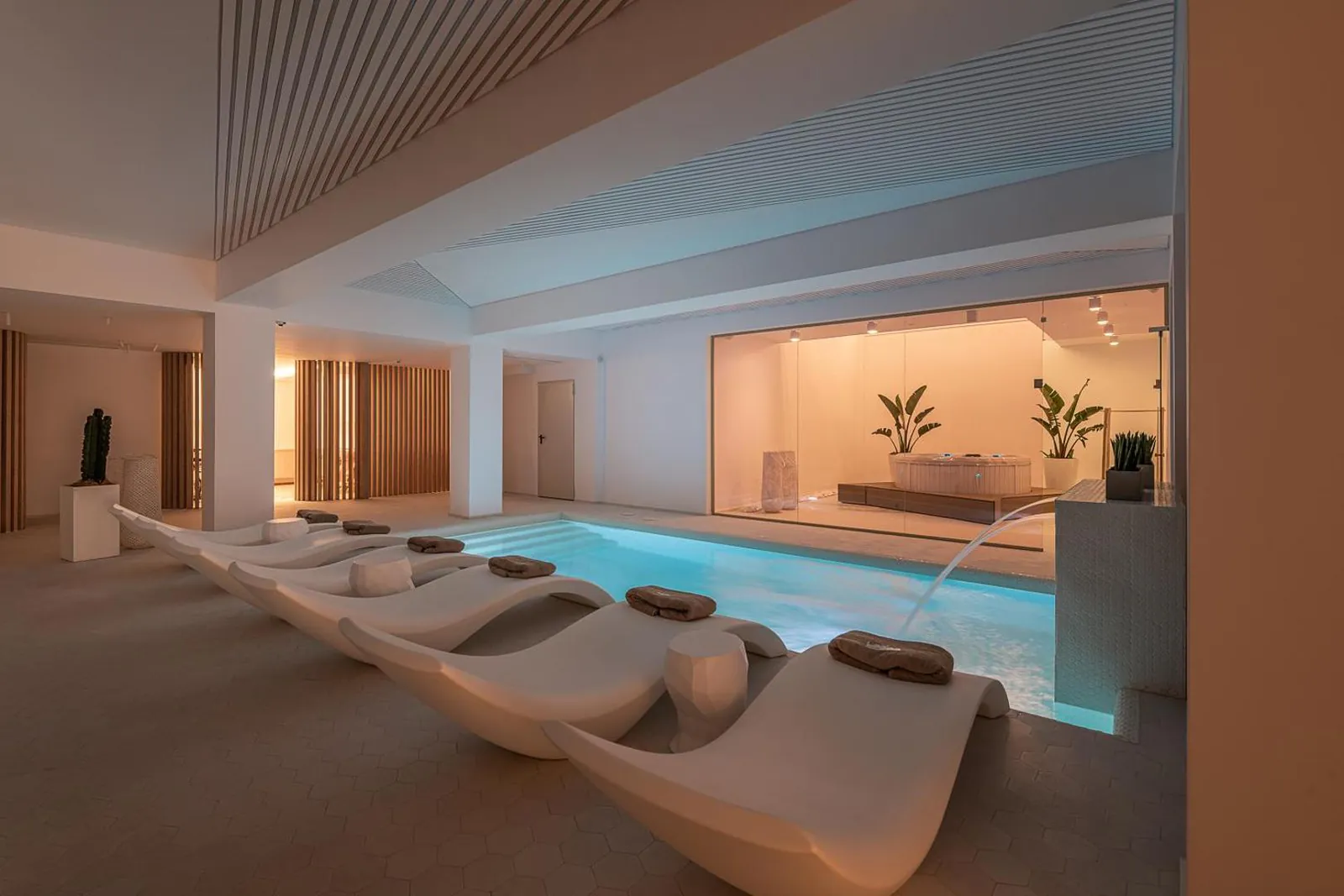 Indoor pool and loungers lit warmly in the evening