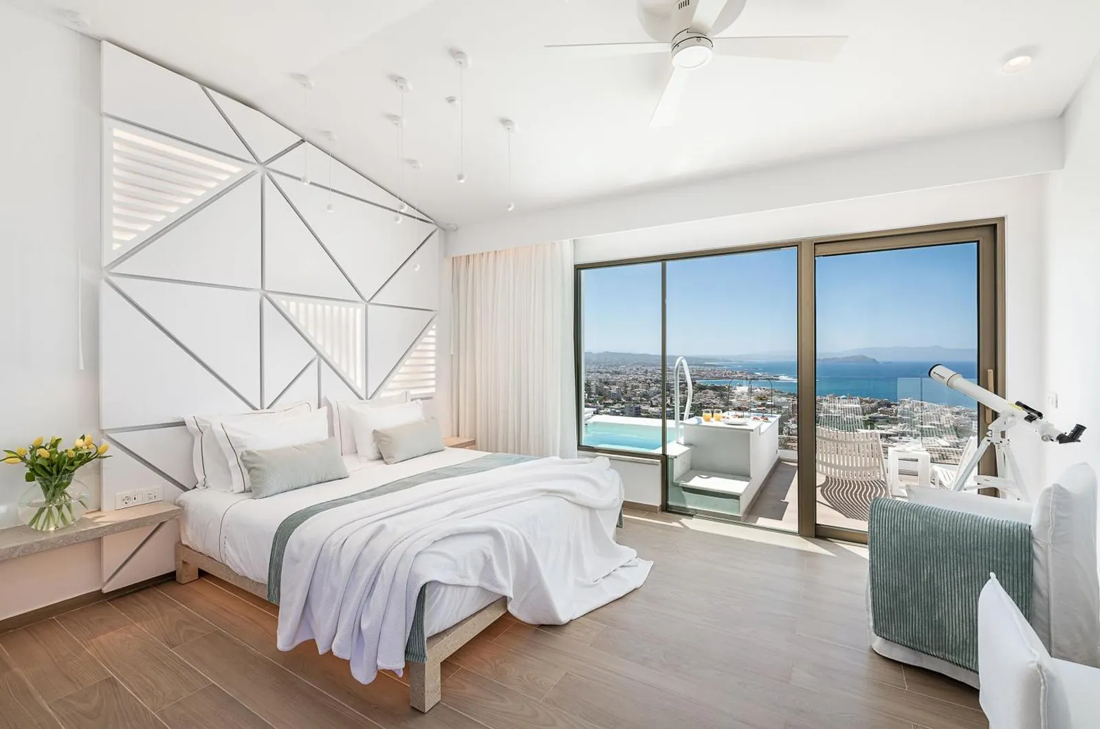 White bedroom with a ceiling fan and glass doors onto a private pool