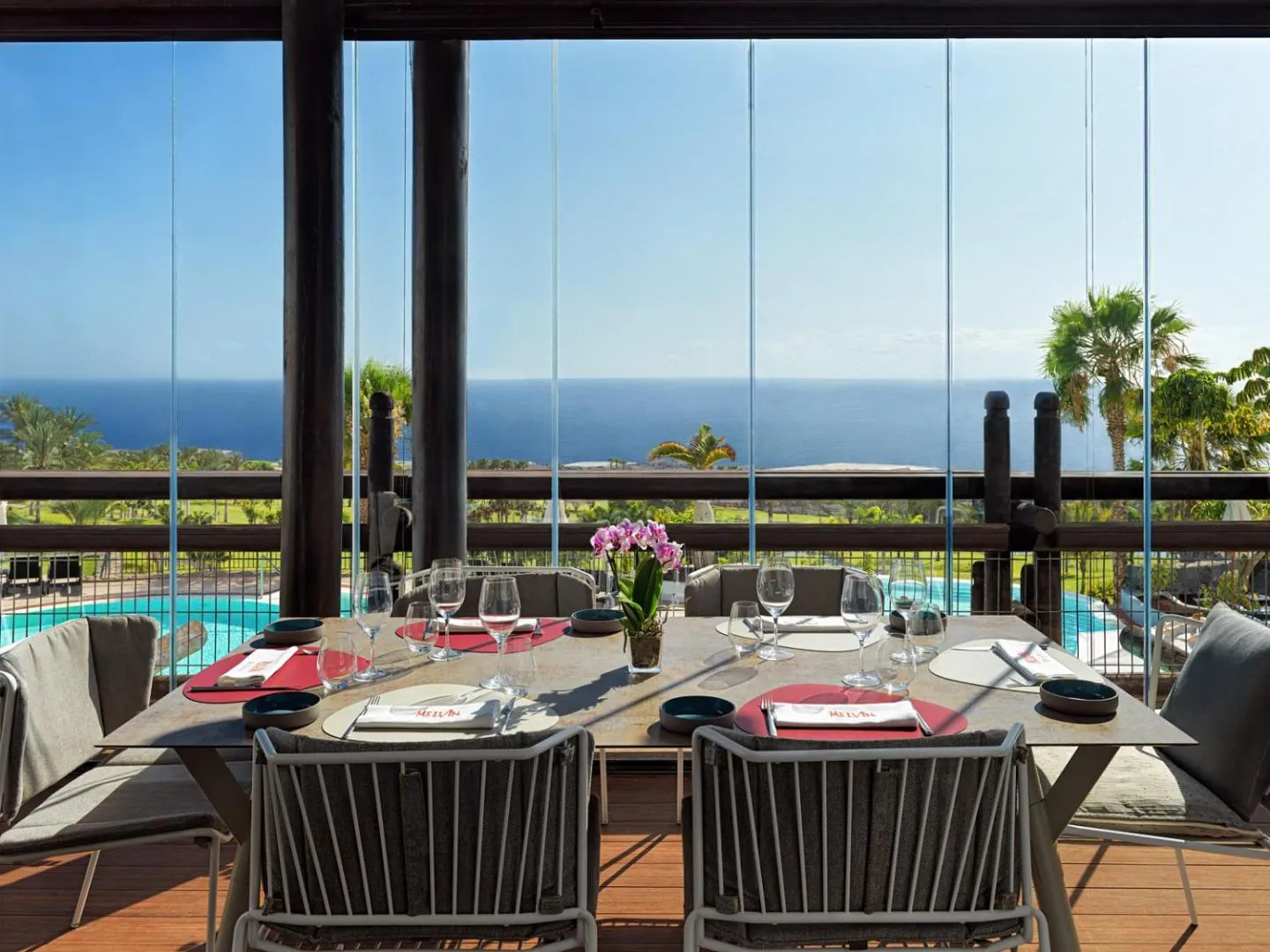 Restaurant terrace with tables set above the pool and the sea