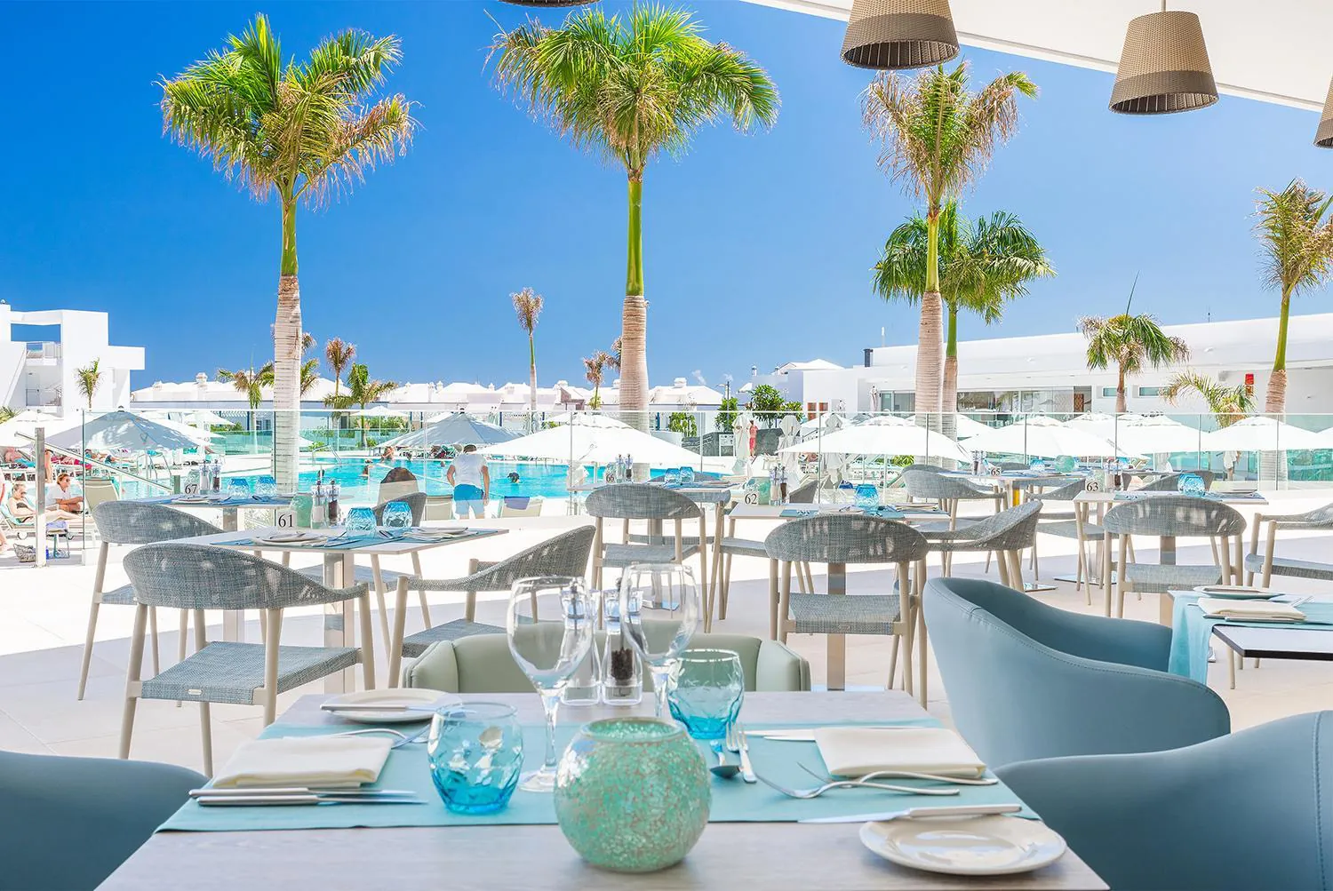 Terrace restaurant tables under parasols above the pool area