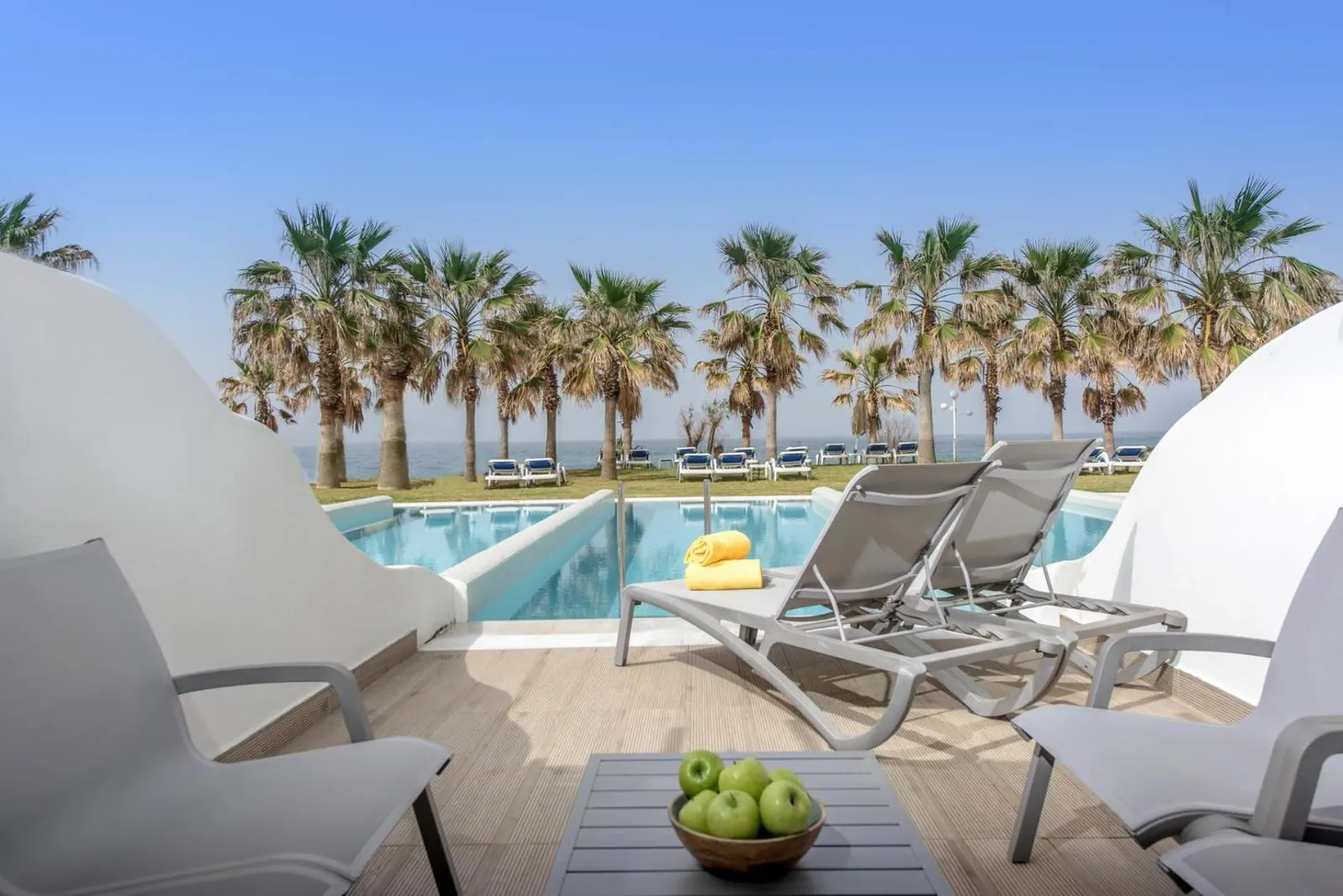 Terrace with loungers overlooking a pool and palms