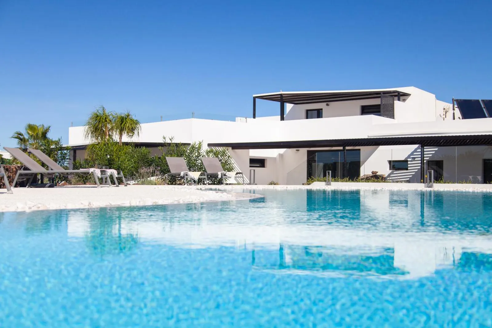 Low view across the pool towards the loungers and white suites