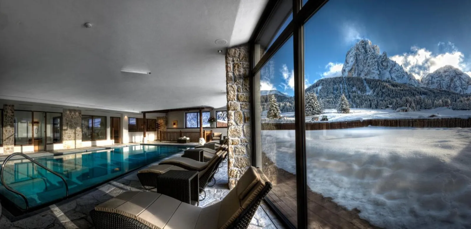 Indoor pool looking out to the snow-covered Dolomites at Monte Pana Dolomites Hotel