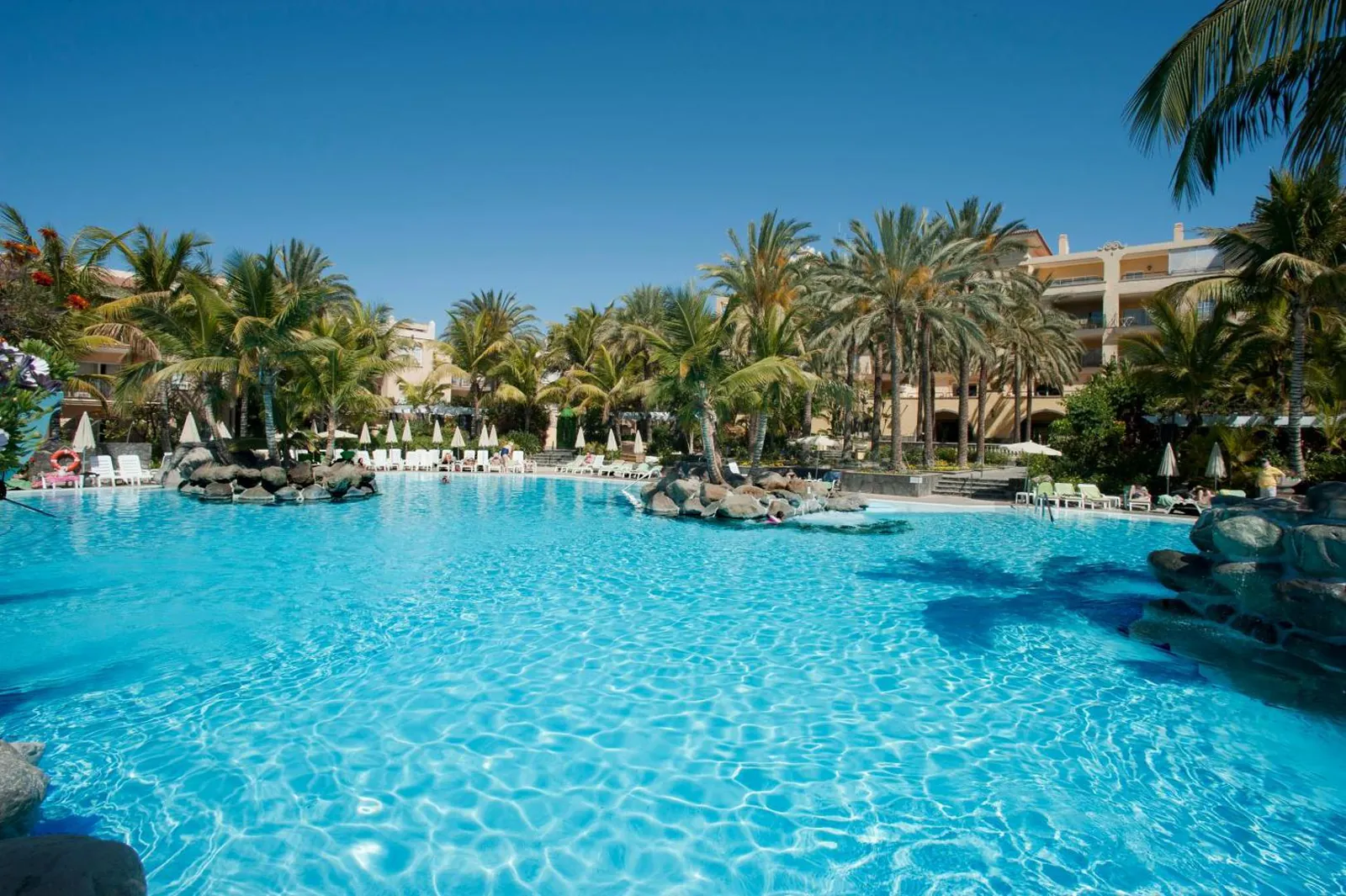 Turquoise main pool with rock islands and palm trees at Palm Oasis Maspalomas