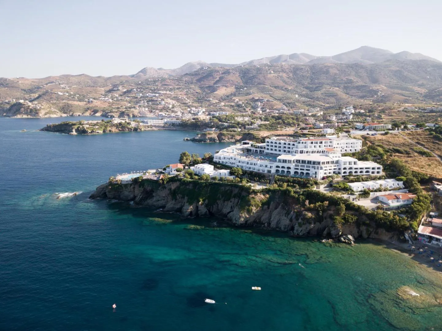 Peninsula Resort and Spa on its headland in the bay of Agia Pelagia, mountains behind