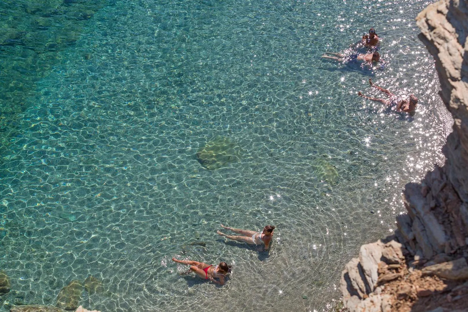 Swimmers in clear shallow water off the rocks below the resort