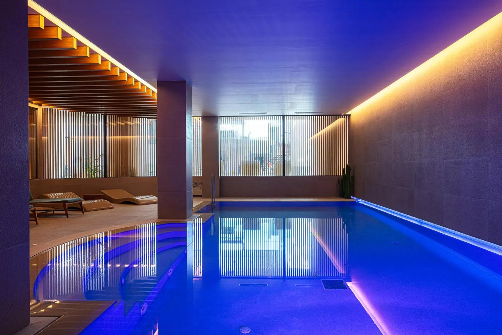 Indoor pool in the spa with blue lighting and loungers