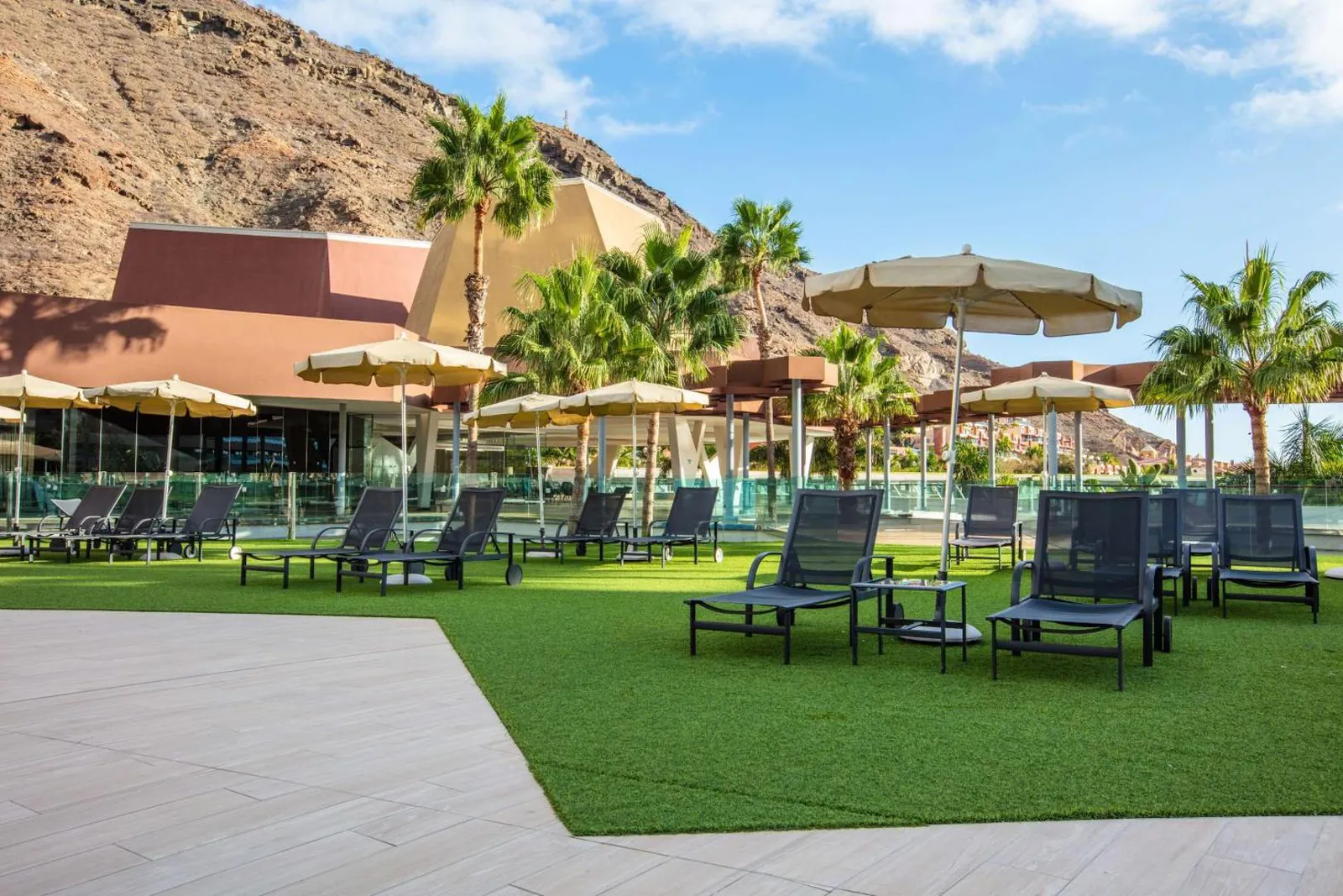 Lawn with sun loungers and parasols beside the pool area