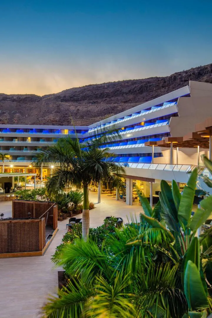 Resort buildings and palms against the hills at sunset