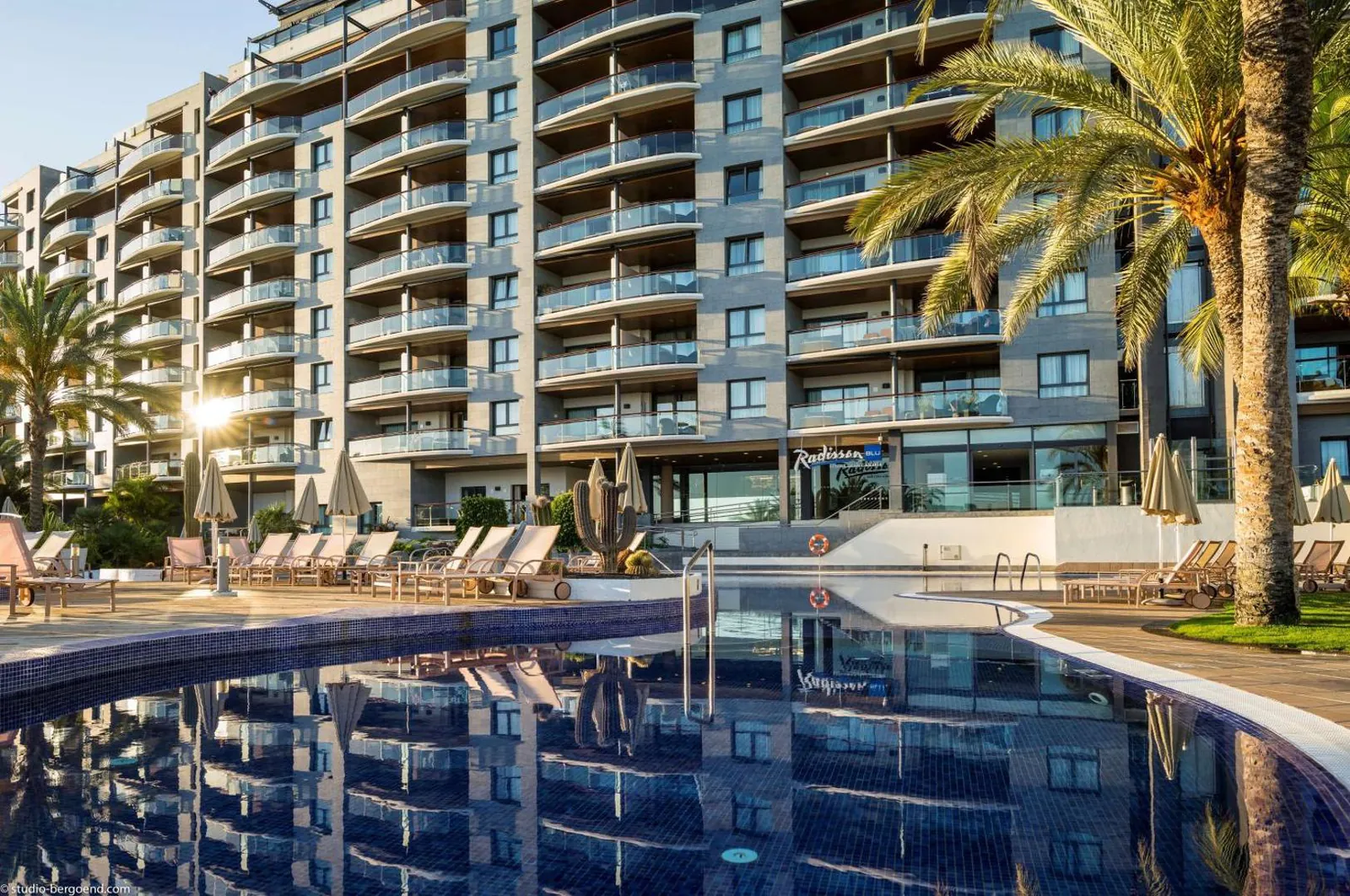 Pool in front of the resort's balconied main building at dusk