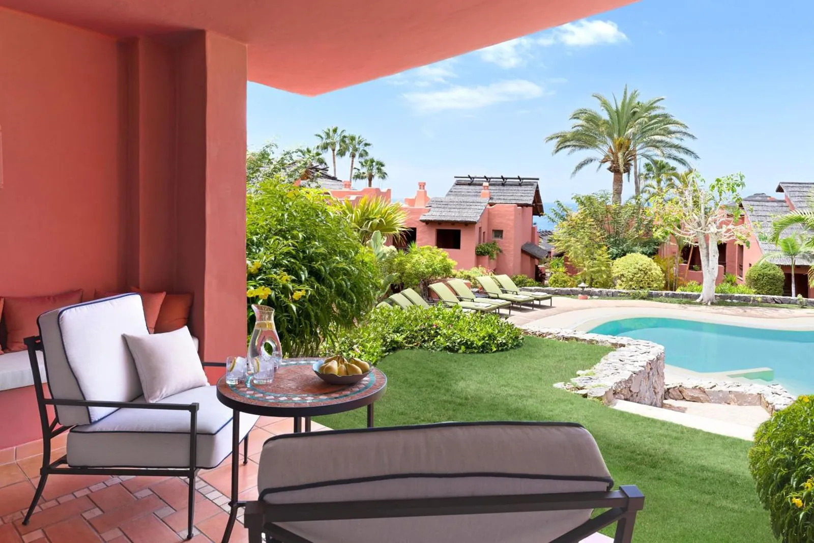 Garden terrace with armchairs looking onto a turquoise pool