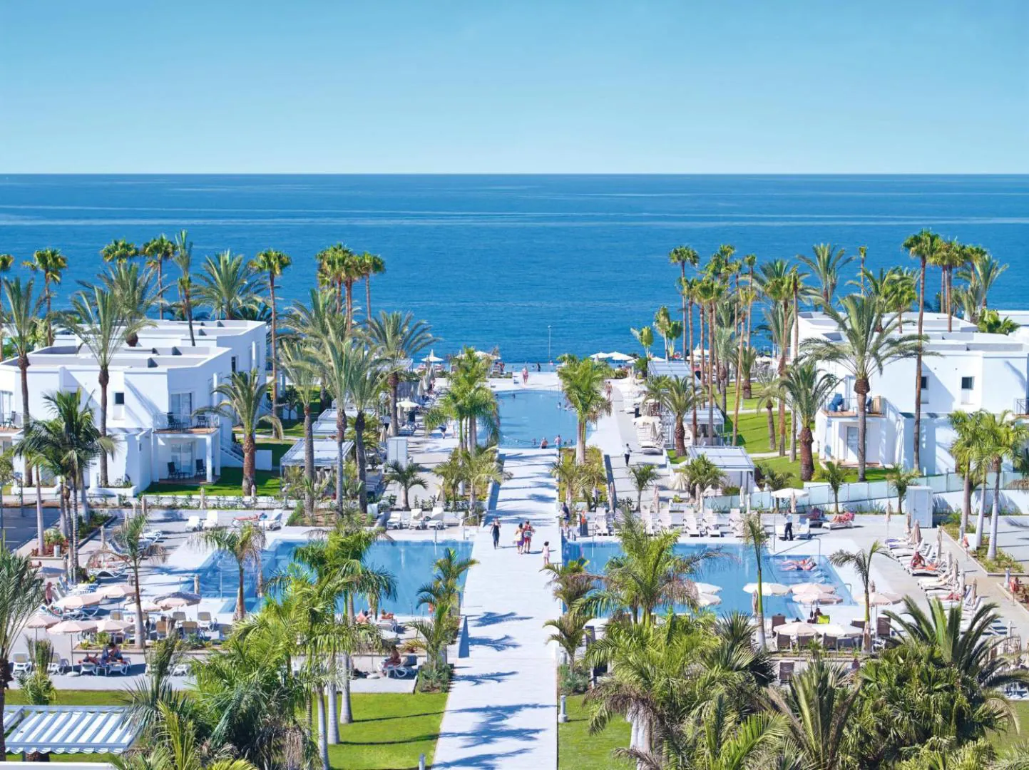 Aerial view over the pool gardens and palm trees to the sea at Meloneras