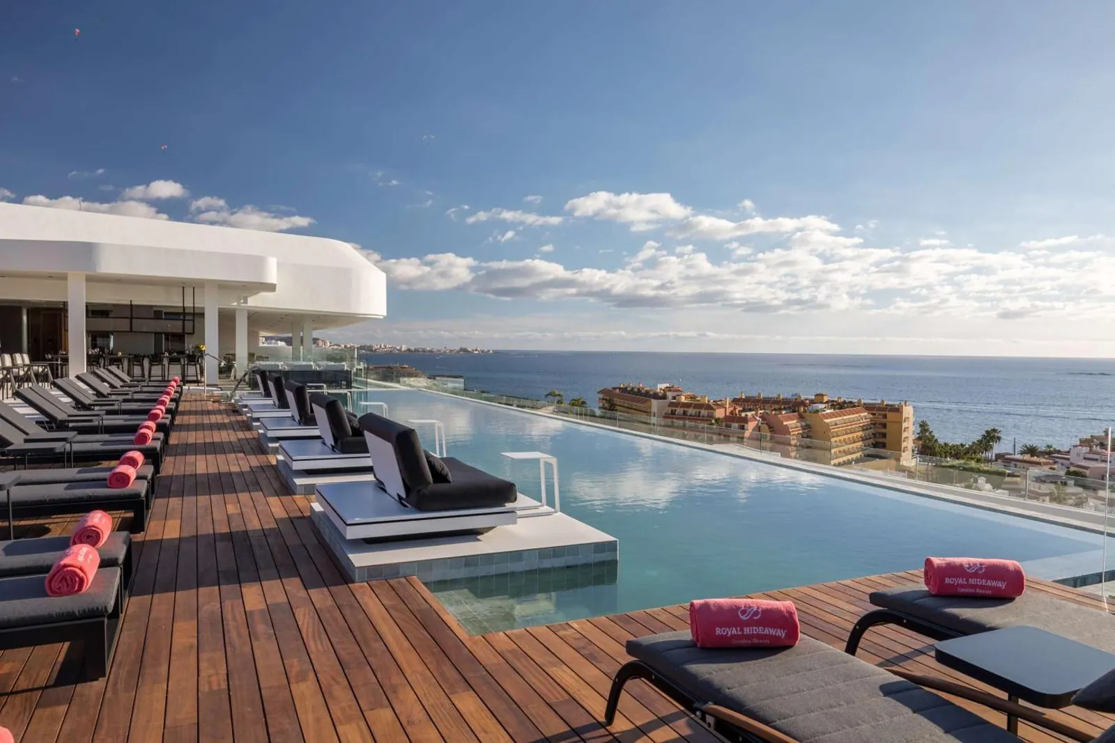Infinity pool and timber deck with sun loungers facing the ocean