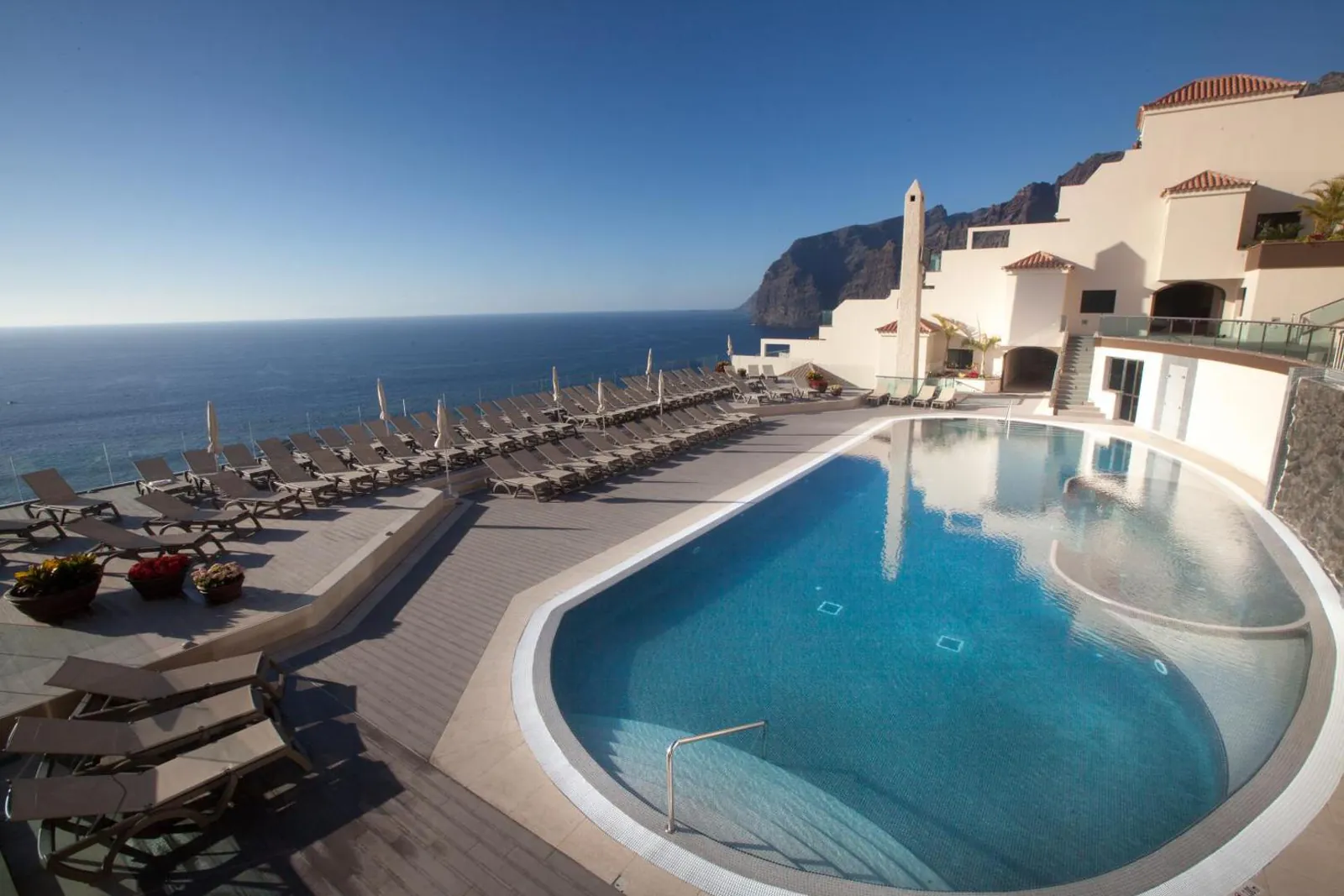 Curved outdoor pool with sun loungers above the sea at Royal Sun Resort, Los Gigantes