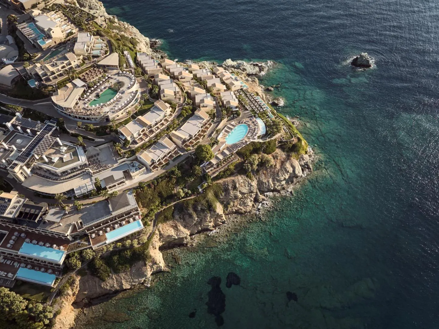Aerial view of the resort stepping down a rocky headland to the sea at Agia Pelagia