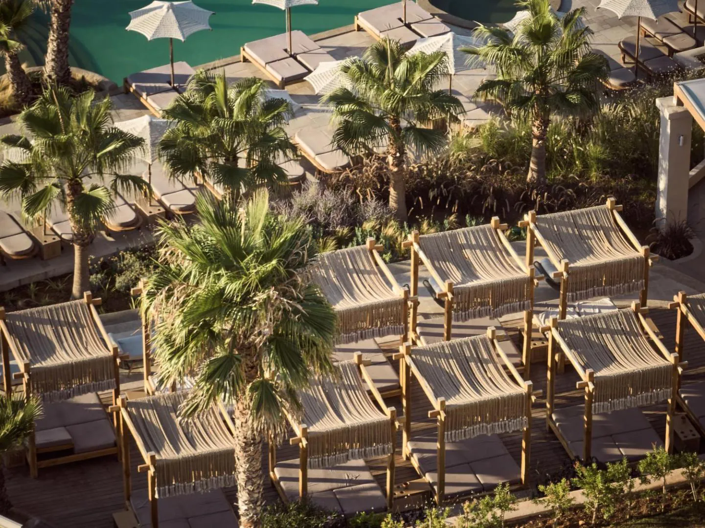Rows of cabana sunbeds under palms beside the pool
