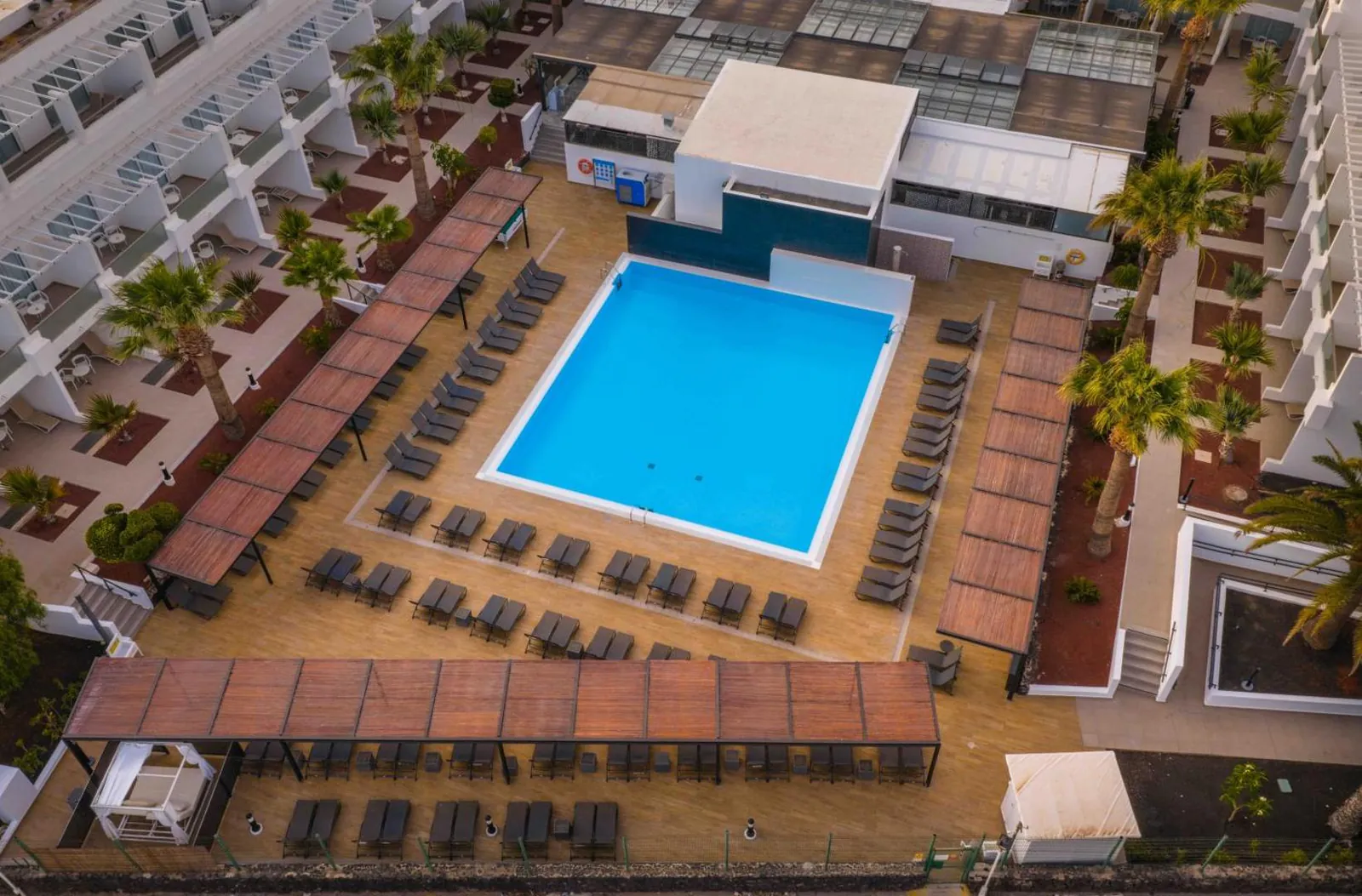 Rectangular pool ringed by loungers and shaded walkways, seen from above