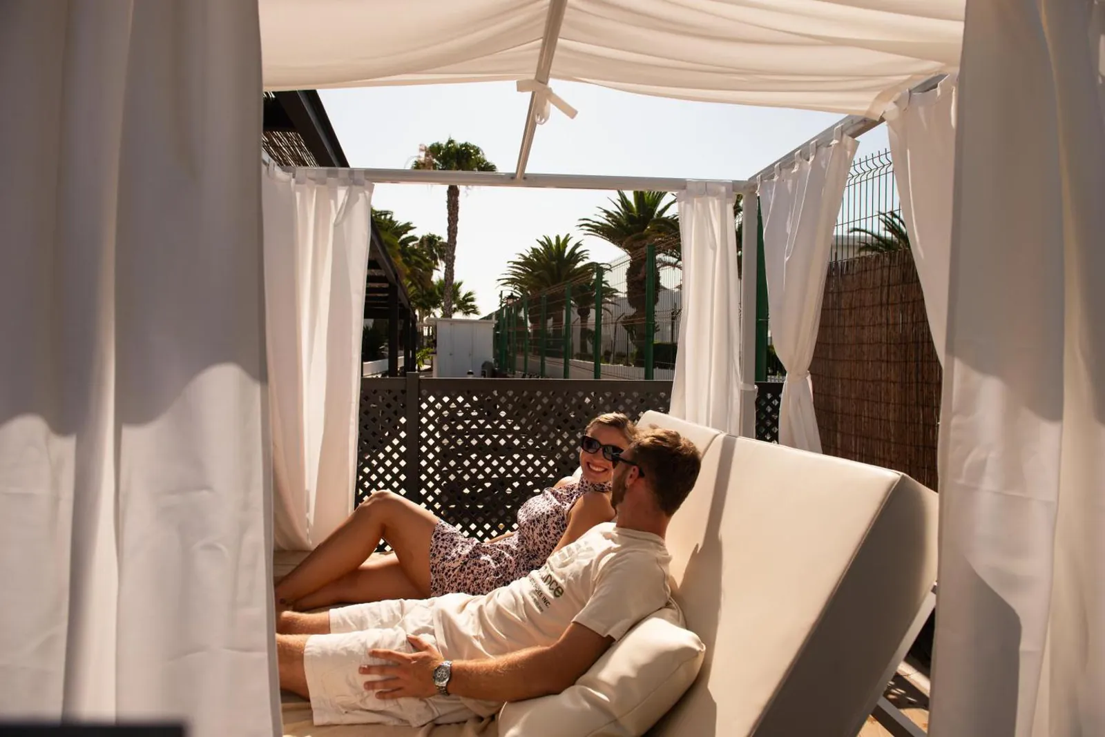 Guest relaxing on a curtained daybed by the pool
