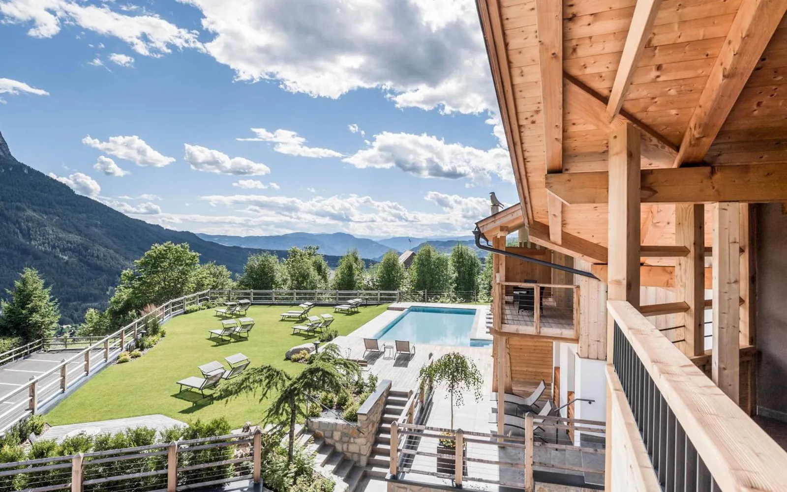 The outdoor pool and garden of Sonus Alpis seen from a wooden balcony