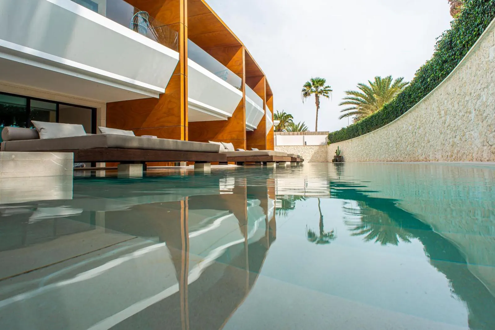 Long heated saltwater pool running past the ground-floor suites at TenSuites, palms reflected in the water