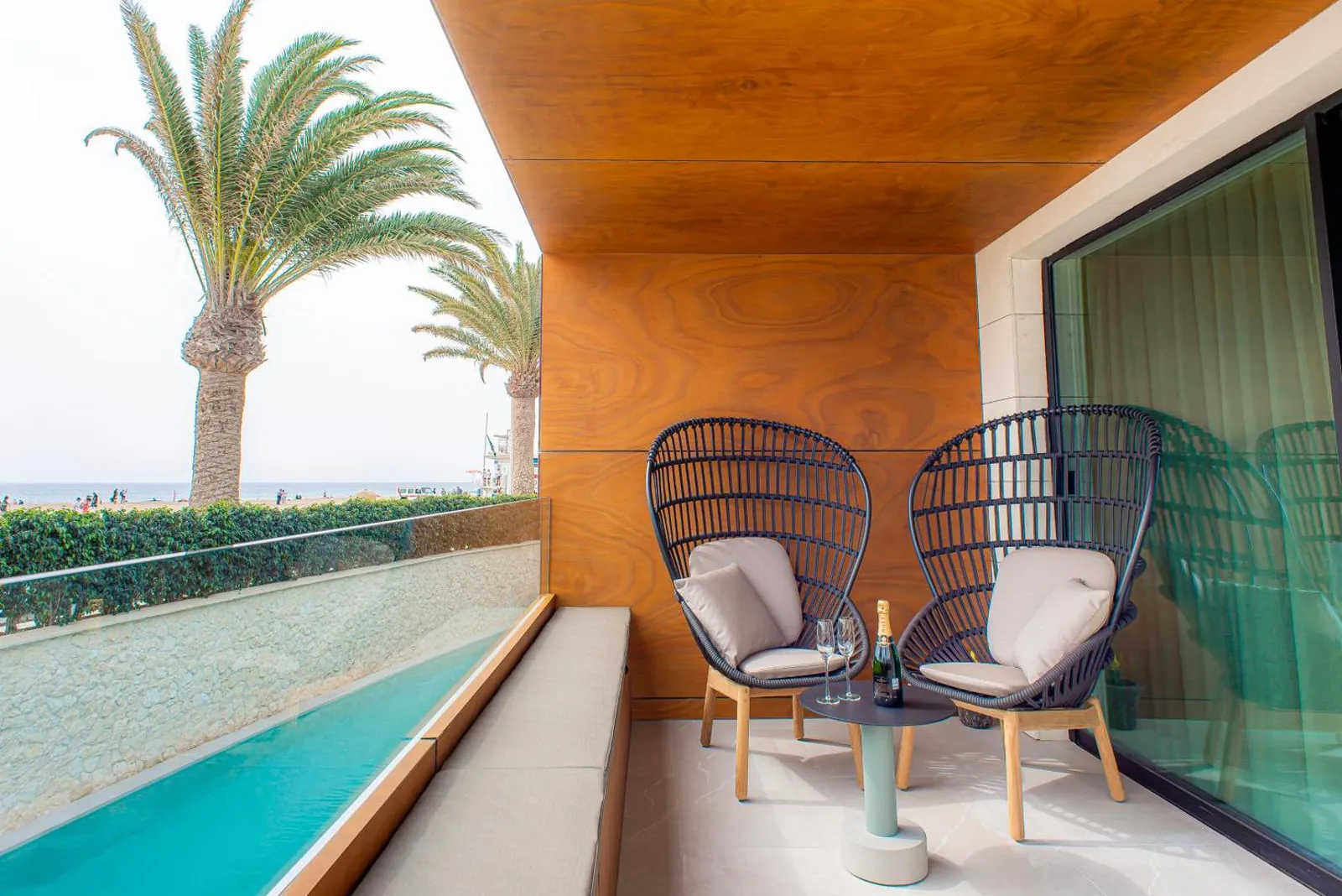 Suite terrace opening straight onto the pool, with palms and a sea glimpse