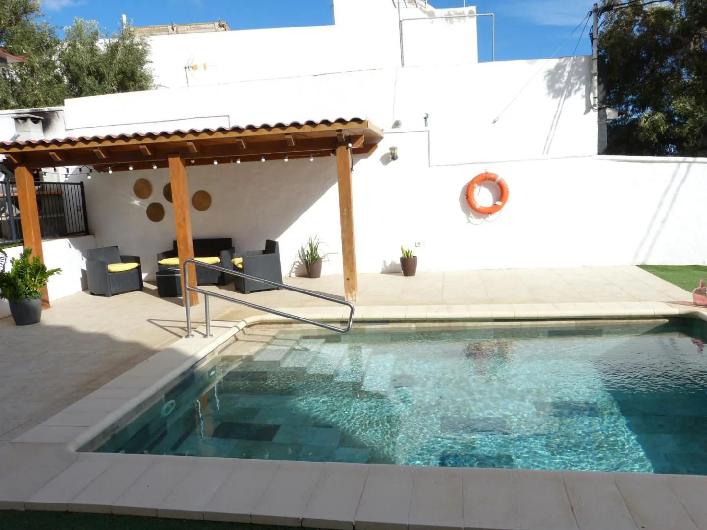 Shaded lounge corner under a wooden pergola, right next to the pool